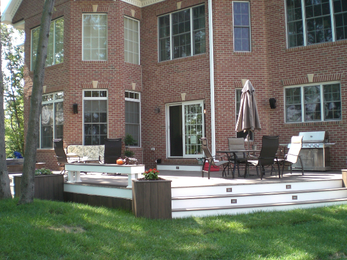 Bench seating area on brown backyard deck with flower boxes